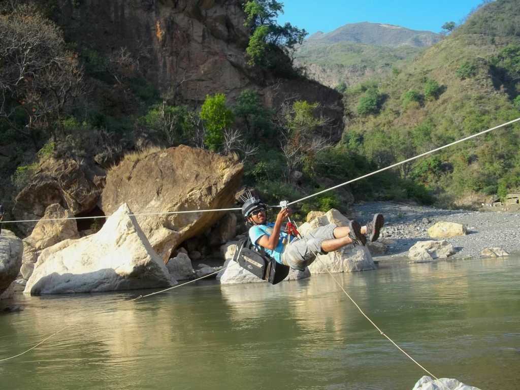 Adventure enthusiasts crossing the Tirthan River