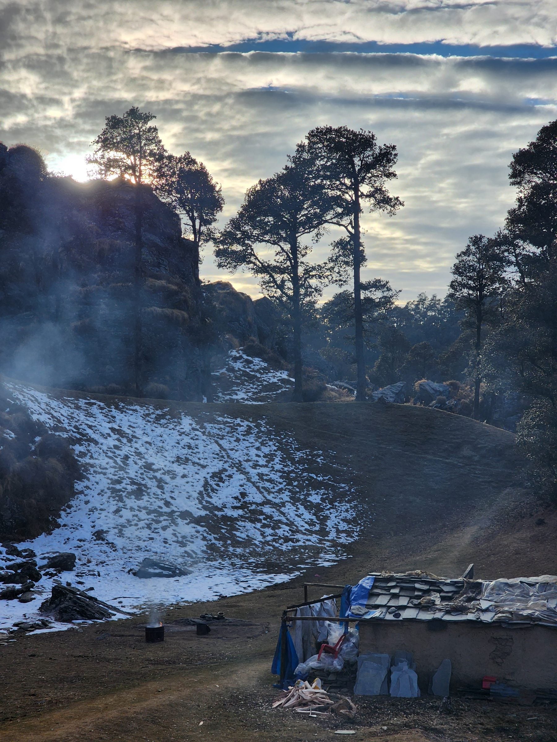 A cozy scene featuring a bonfire amidst a rocky hillside in Jibhi Valley, Himachal Pradesh, India.