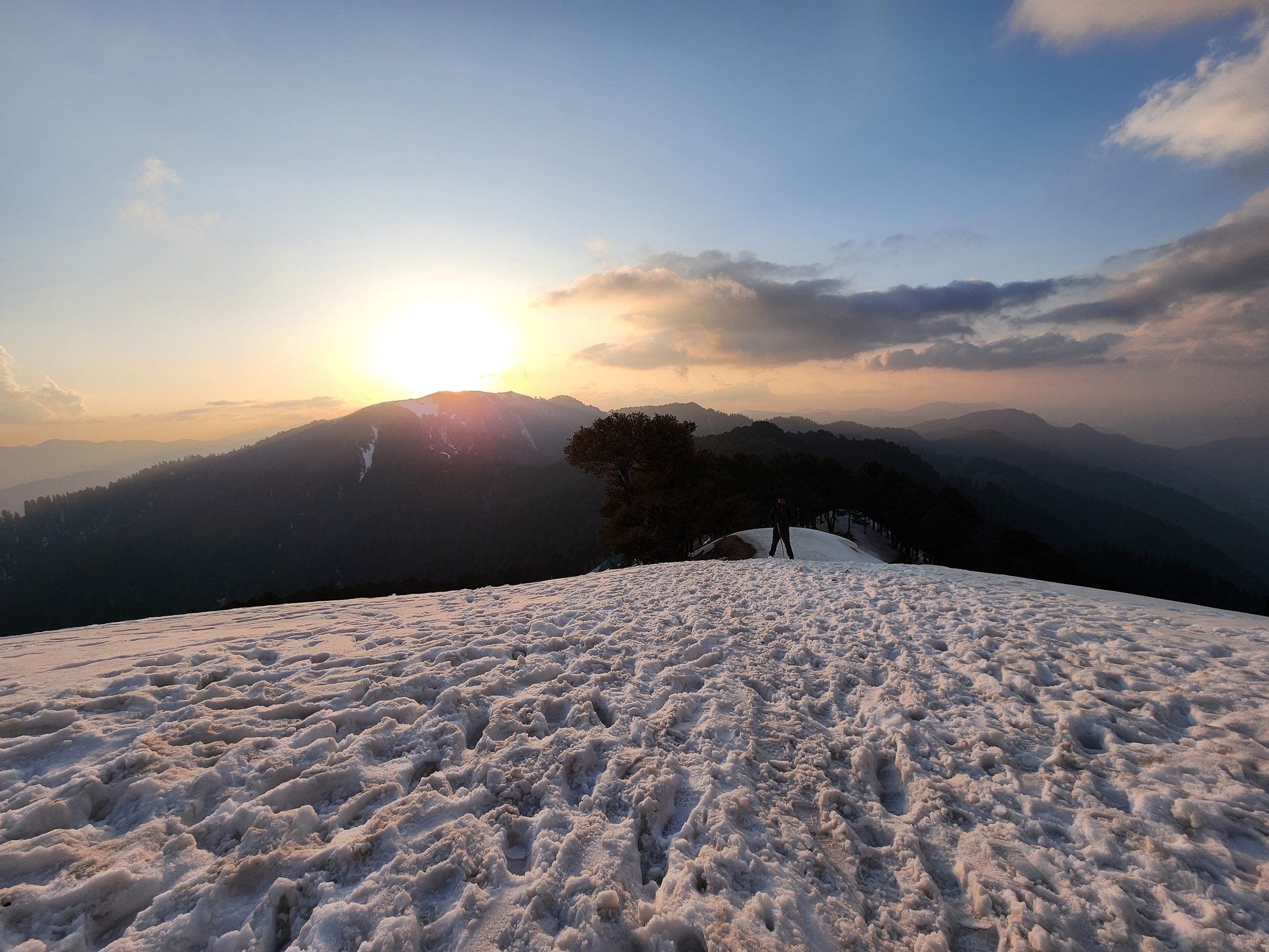 A lone traveler stands amidst a snow-covered landscape in Shoja Valley, Himachal Pradesh, India.