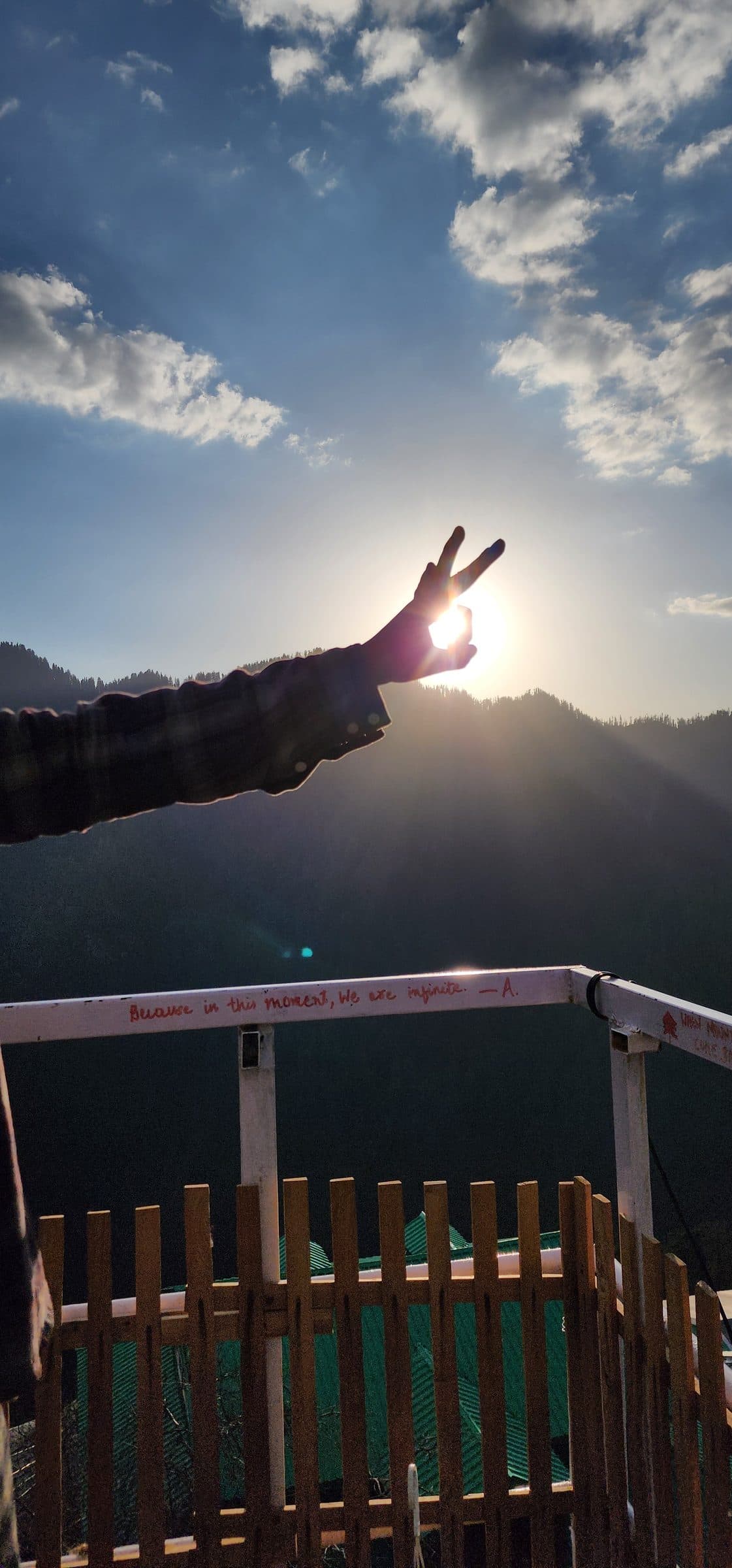 A vibrant green wooden fence overlooks a scenic valley landscape in Jibhi, Himachal Pradesh, India, hinting at a peaceful retreat.