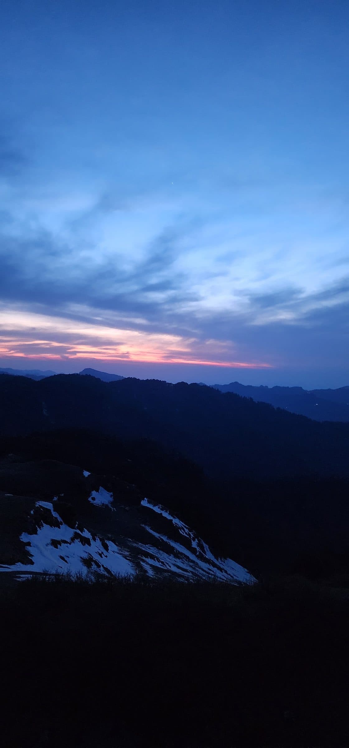 Dark silhouette of rolling hills and sky with soft clouds